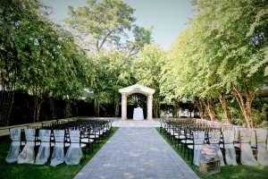 photo of grand courtyard at Brownstone Gardens. Paver path leads to arch with chairs along sides of the path.